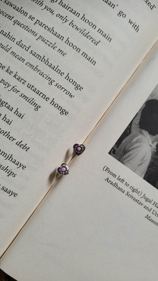 Heart-shaped earrings with purple meenakari on a book page