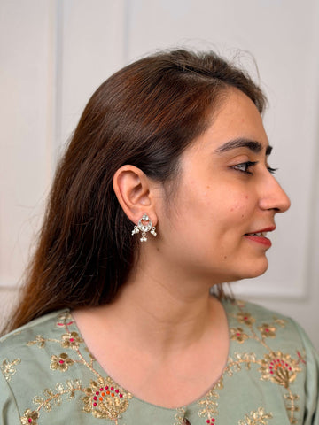 A close-up lifestyle shot of a woman wearing a silver-toned, kundan chandbali earrings with white stones and pearls.