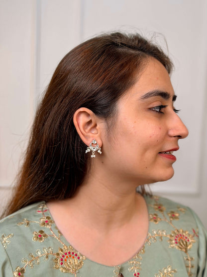 A close-up lifestyle shot of a woman wearing a silver-toned, kundan chandbali earrings with white stones and pearls.