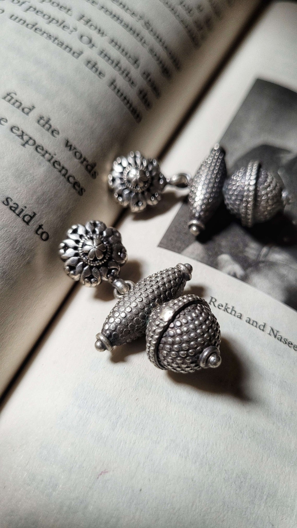 Silver acorn-shaped earrings on an open book