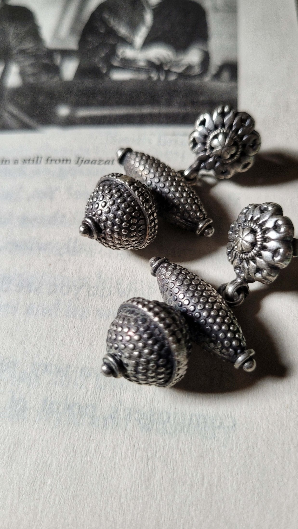 Pair of Riddhita silver earrings on a light gray surface with a blurred background