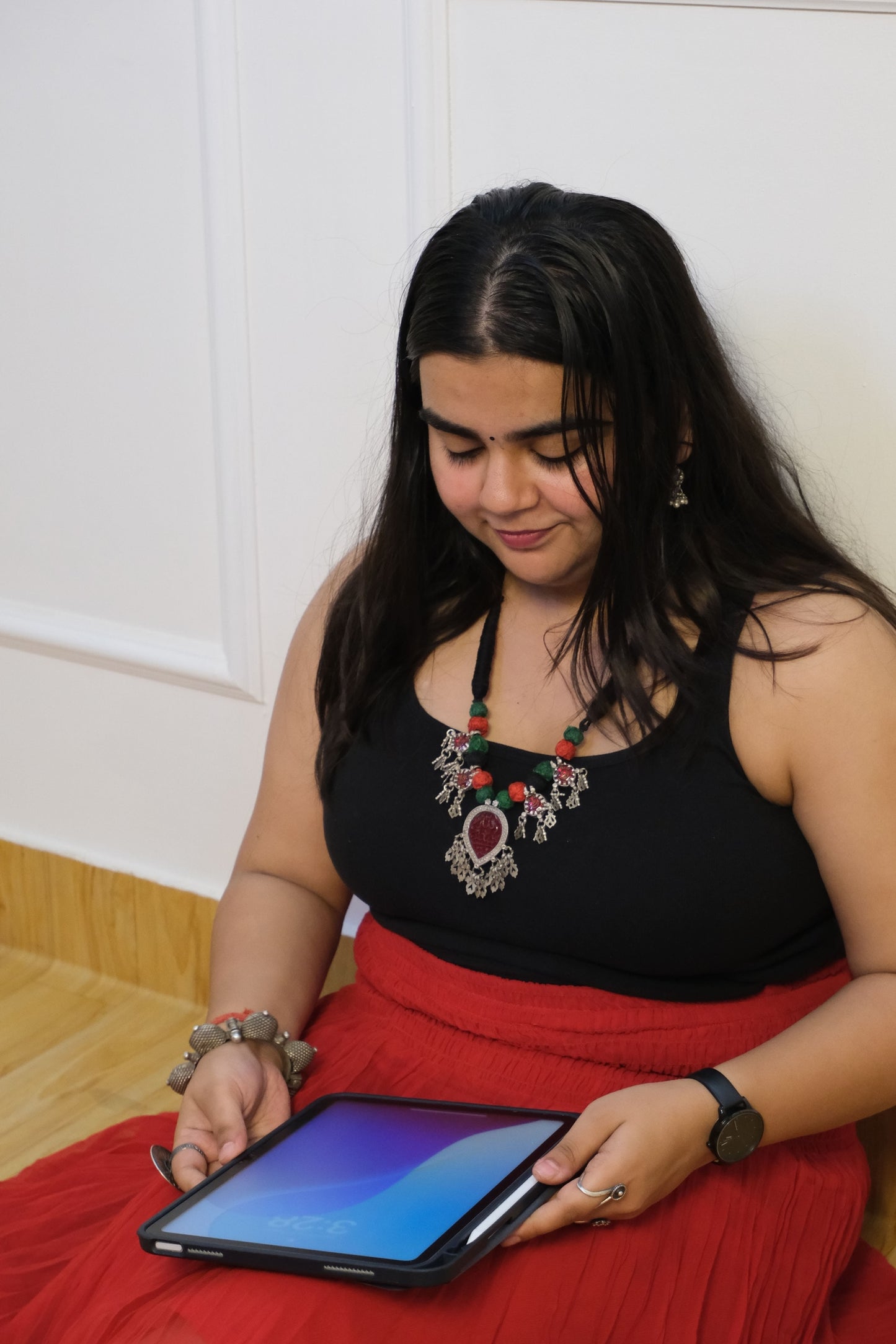 Woman lying on a white surface holding a tablet with a red garment.