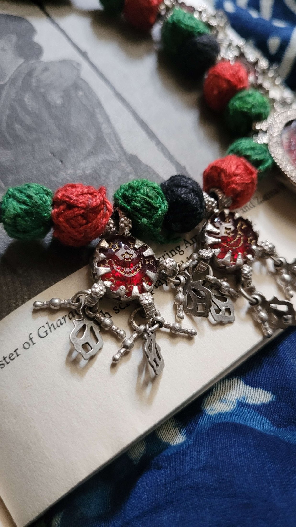 Saaki Vintage Necklace with colorful beads and silver charms on a textured surface