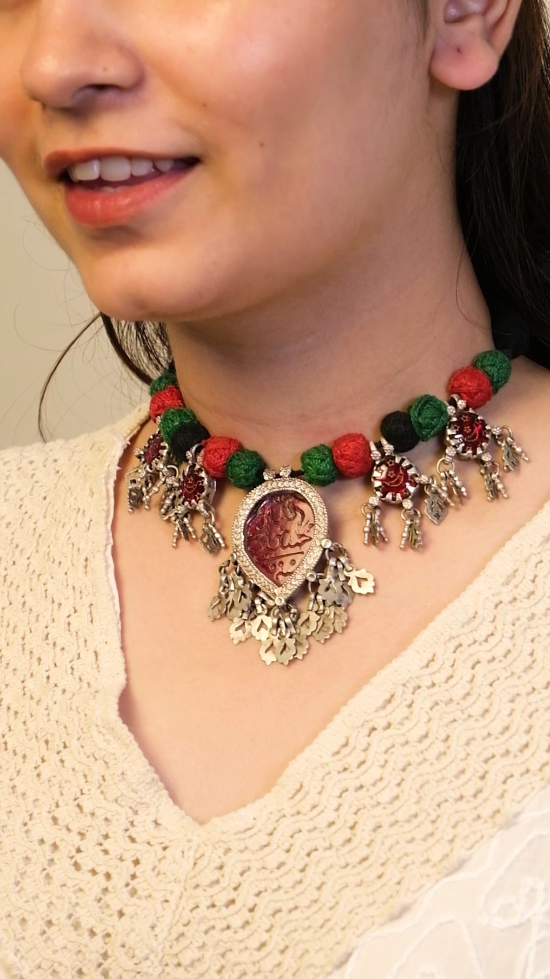 Close-up of a person wearing a decorative necklace with red and green beads.