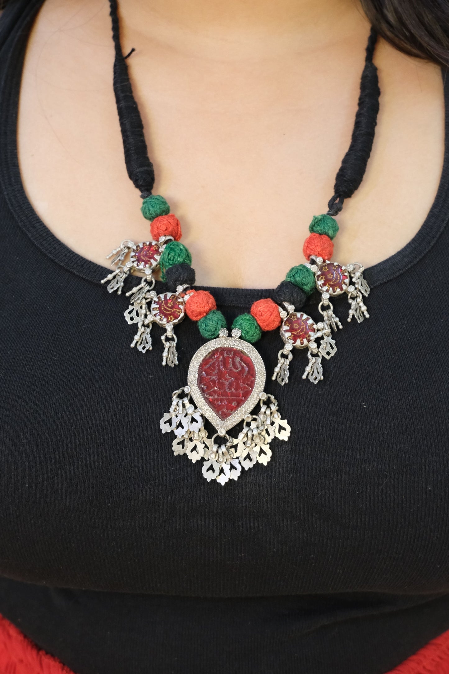 Decorative necklace with red and green beads on a black background