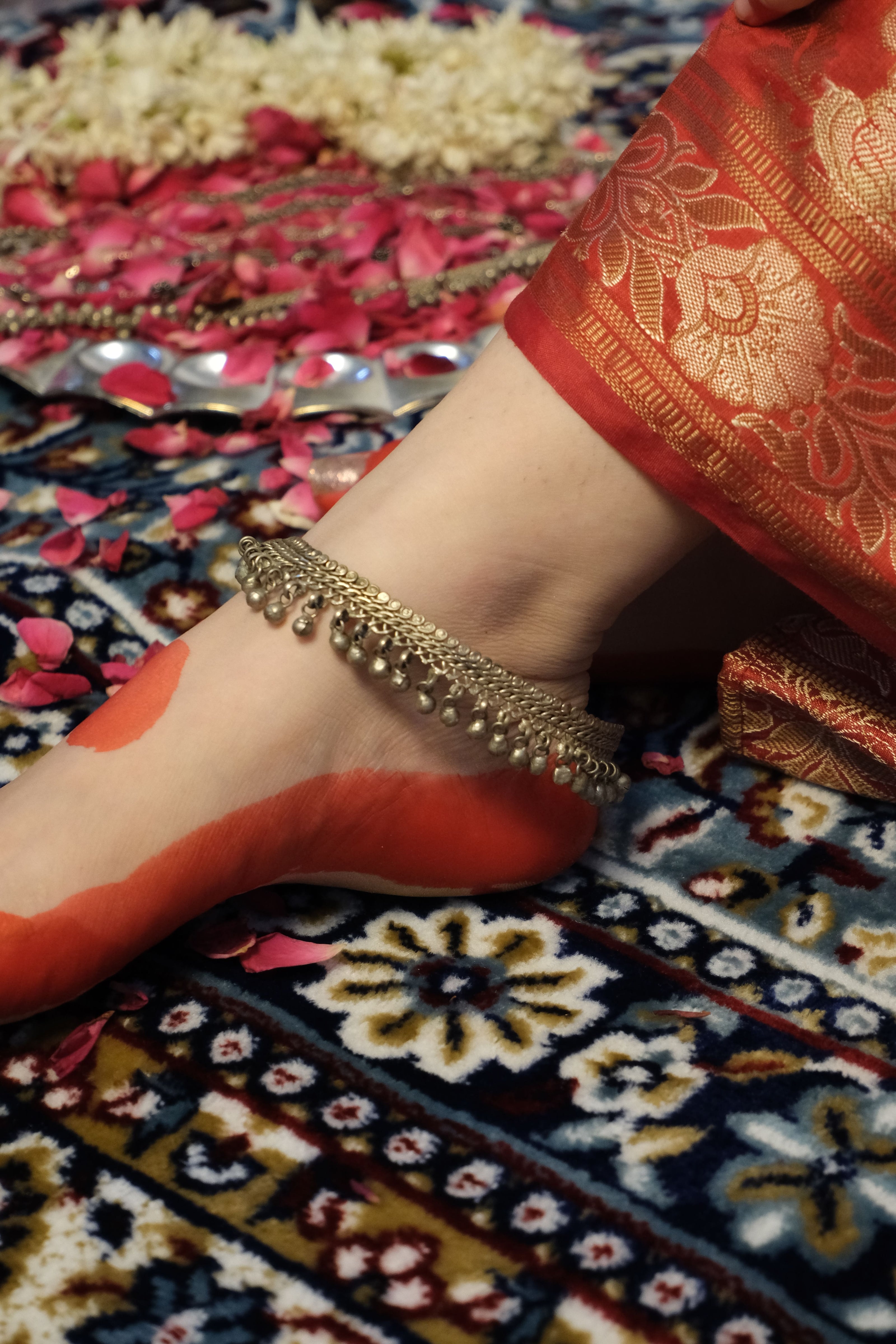 Close-up of a leg wearing anklet on a patterned fabric background