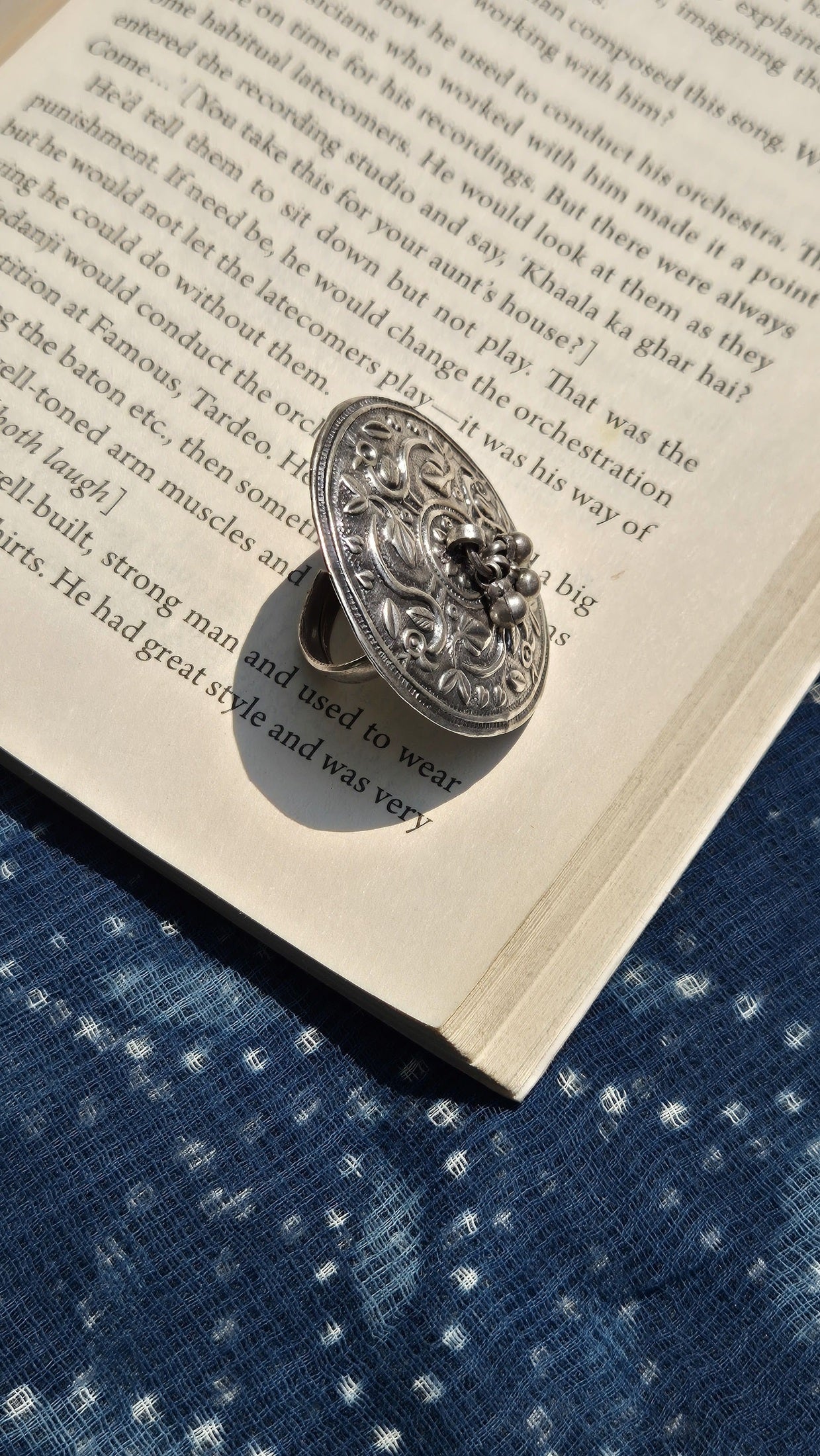 Decorative silver ring on an open book with a blue fabric background