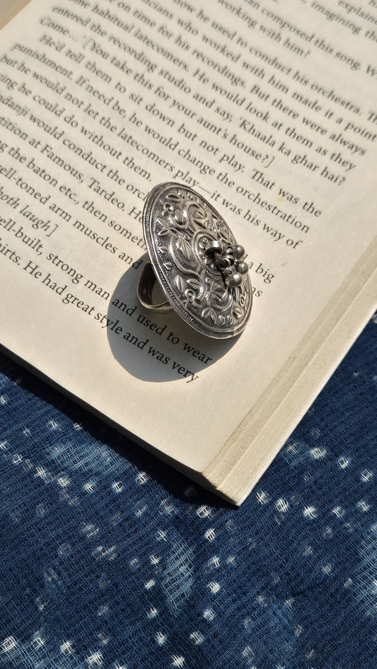 Decorative silver ring on an open book with a blue fabric background