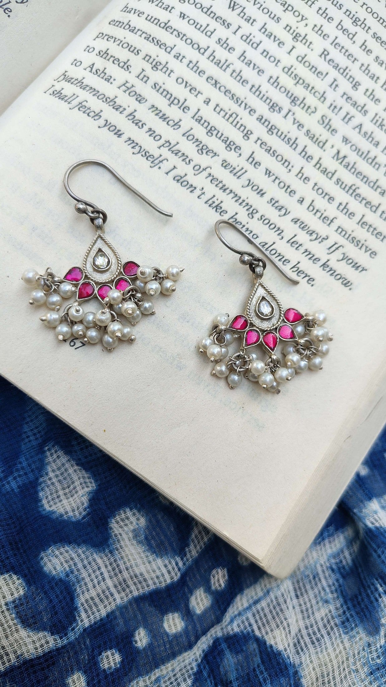 Pair of silver earrings with pink kundan stones on a book | Sadabahaar Jewelry
