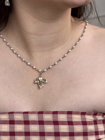 Necklace with a gold plated silver kundan pendant worn by a person, with a checkered fabric background.