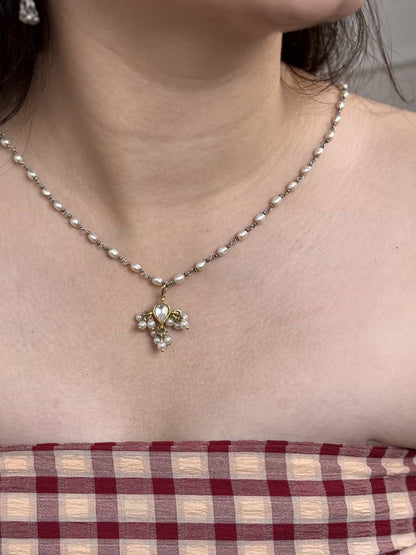 Necklace with a gold plated silver kundan pendant worn by a person, with a checkered fabric background.