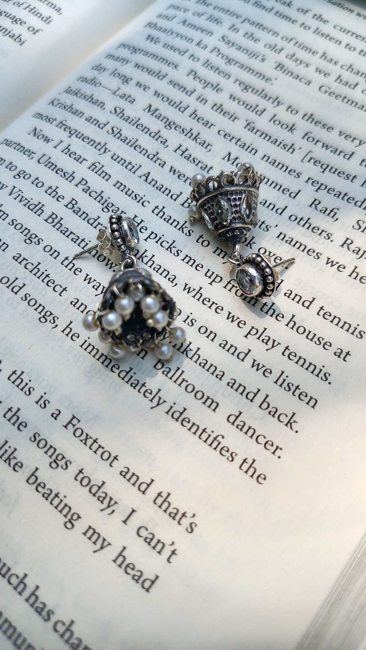 Pair of silver earrings with pearls on an open book
