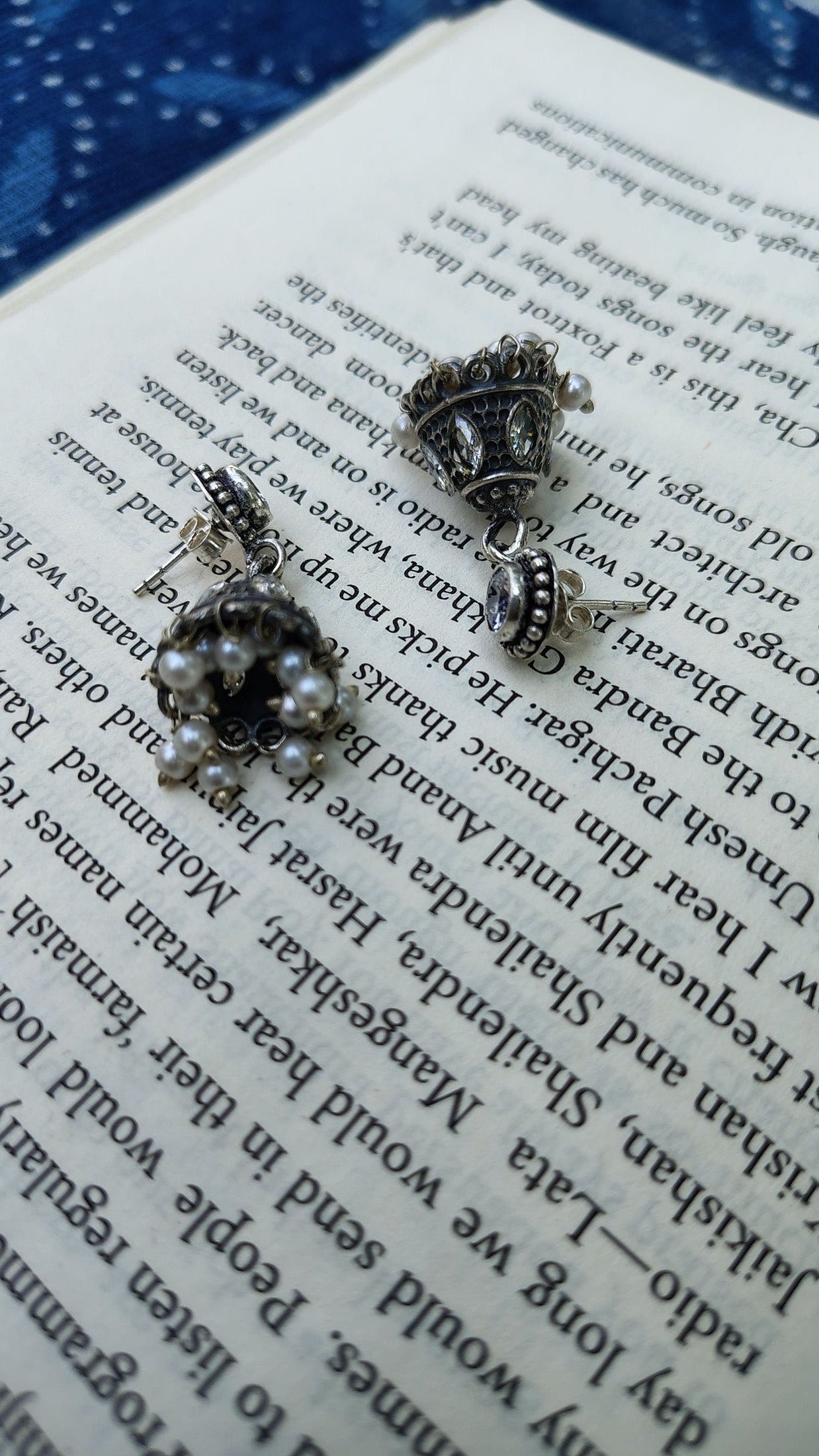 Pair of silver earrings with pearls on an open book