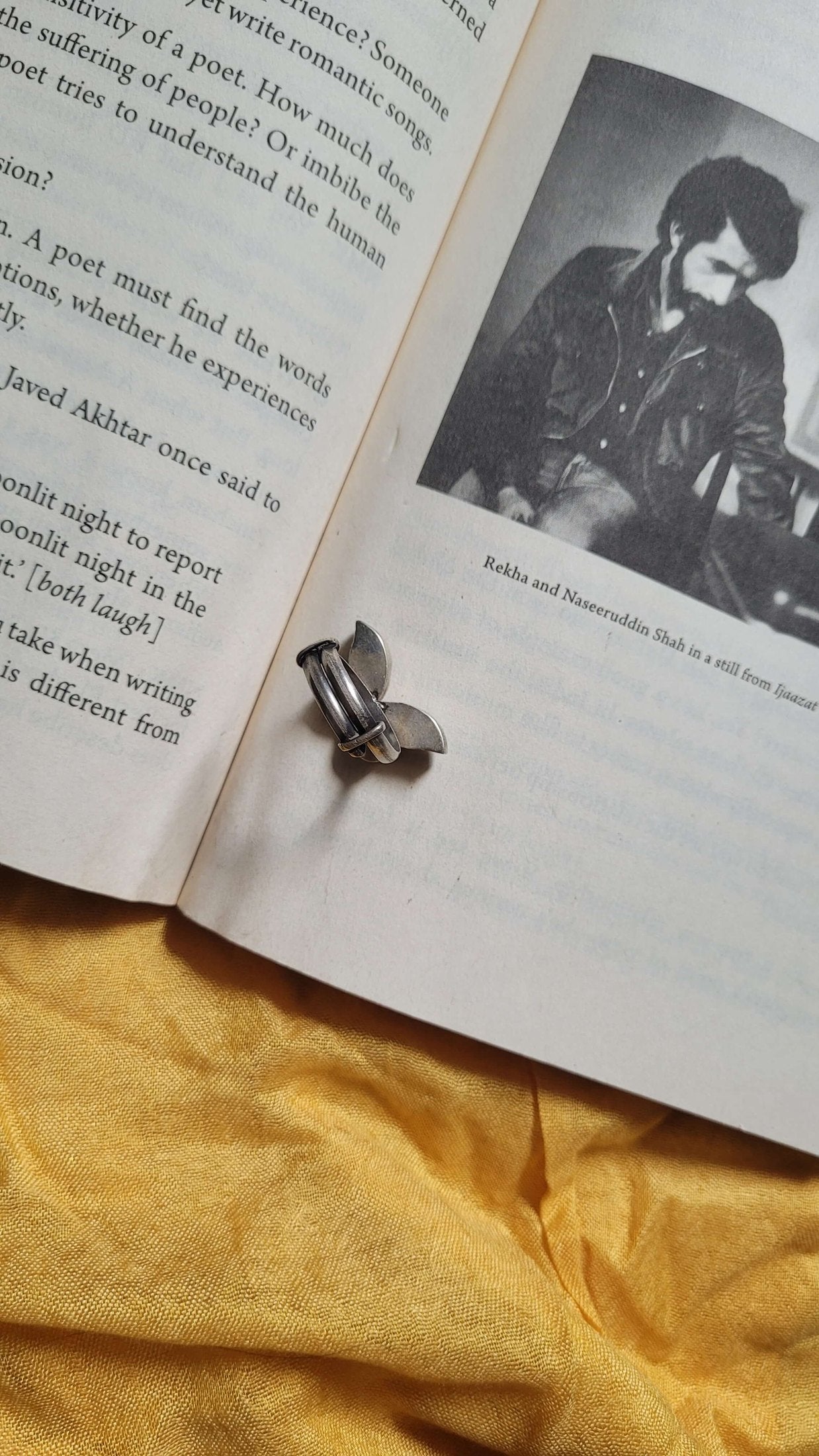 Open book with Shataakshi Ring on a yellow fabric background