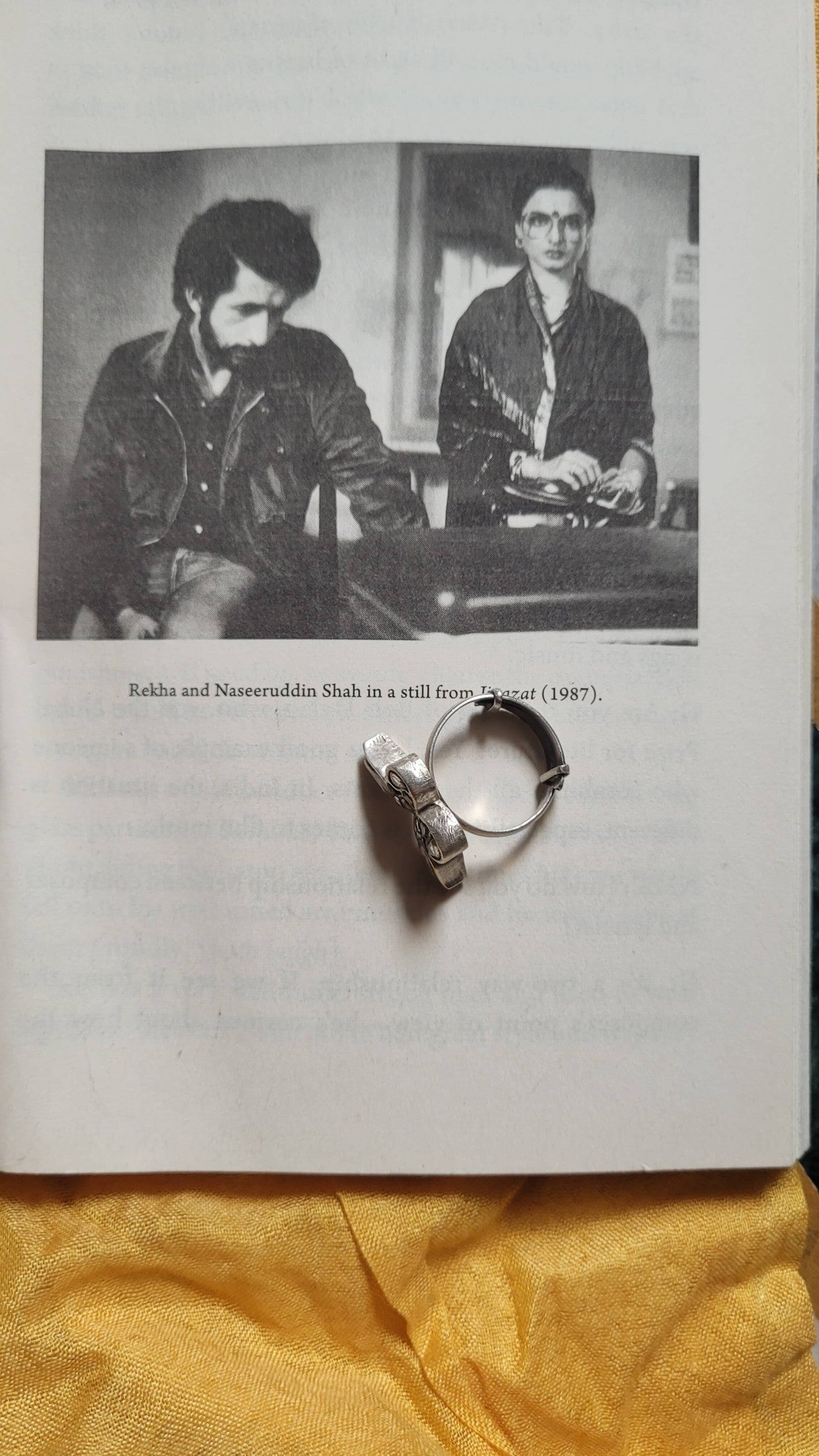 Black and white photo of two people sitting together with Shataakshi Ring on a yellow fabric background.