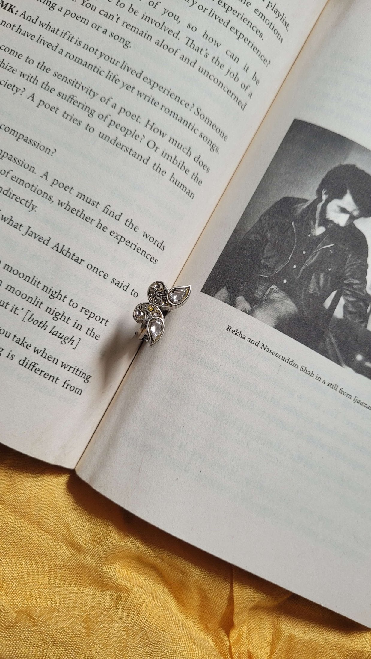Open book with a photo of a person and Shataakshi Ring on a yellow fabric background