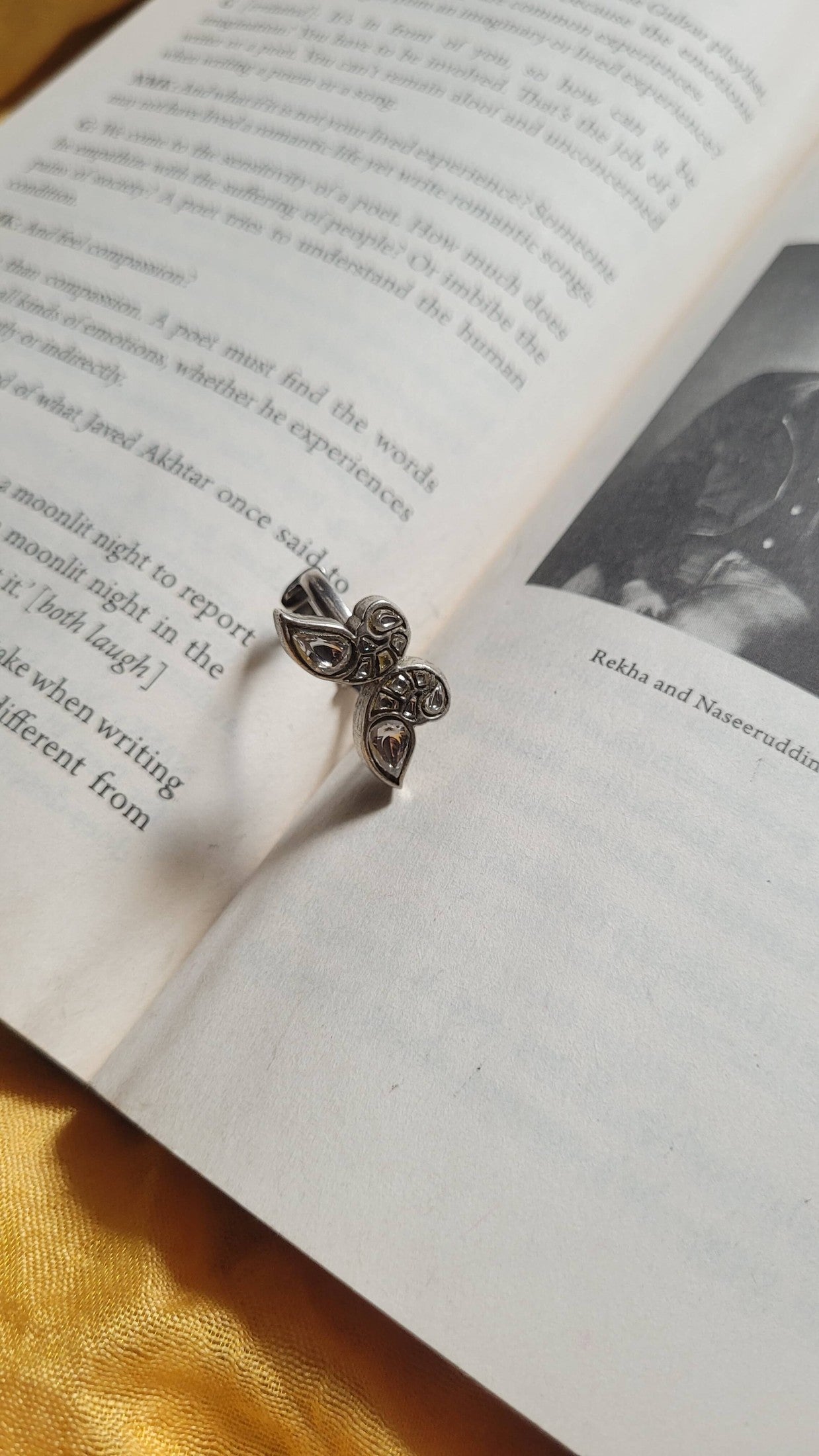 Silver ring with floral design on an open book