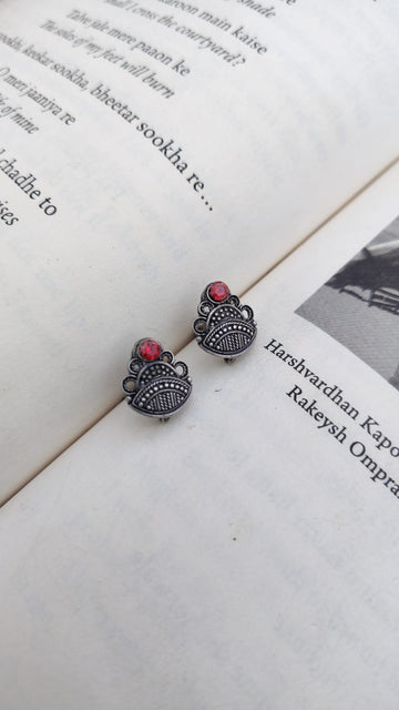 Pair of silver earrings with red stones on an open book