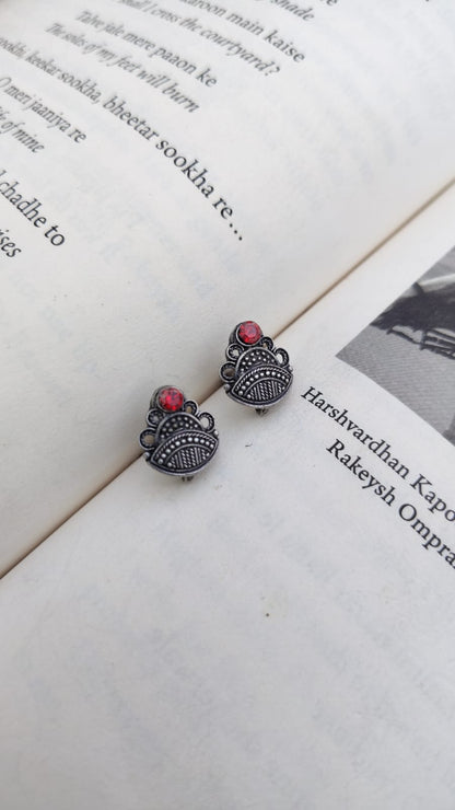 Pair of silver earrings with red stones on an open book
