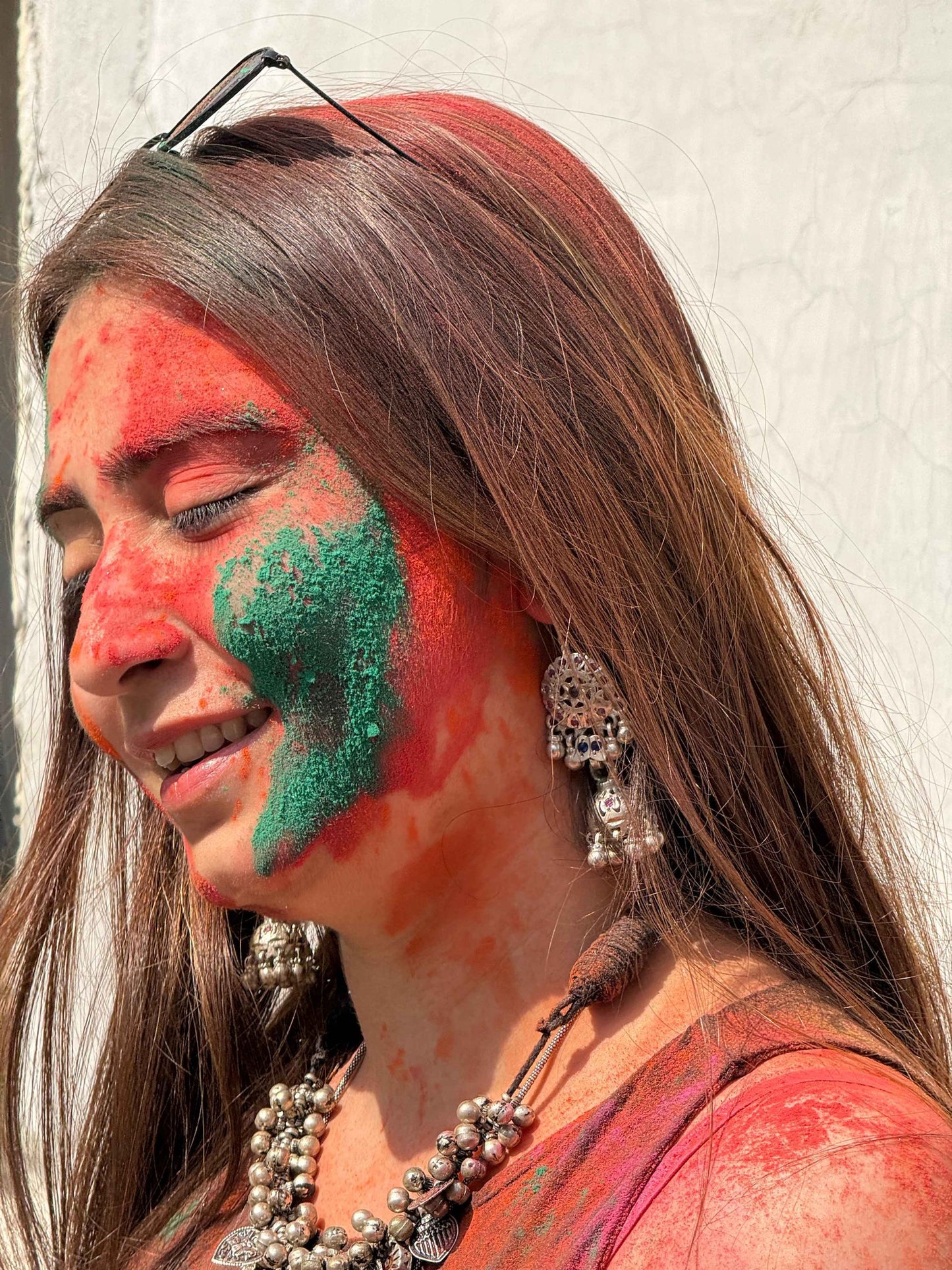 Woman with red and green paint on her face against a white wall