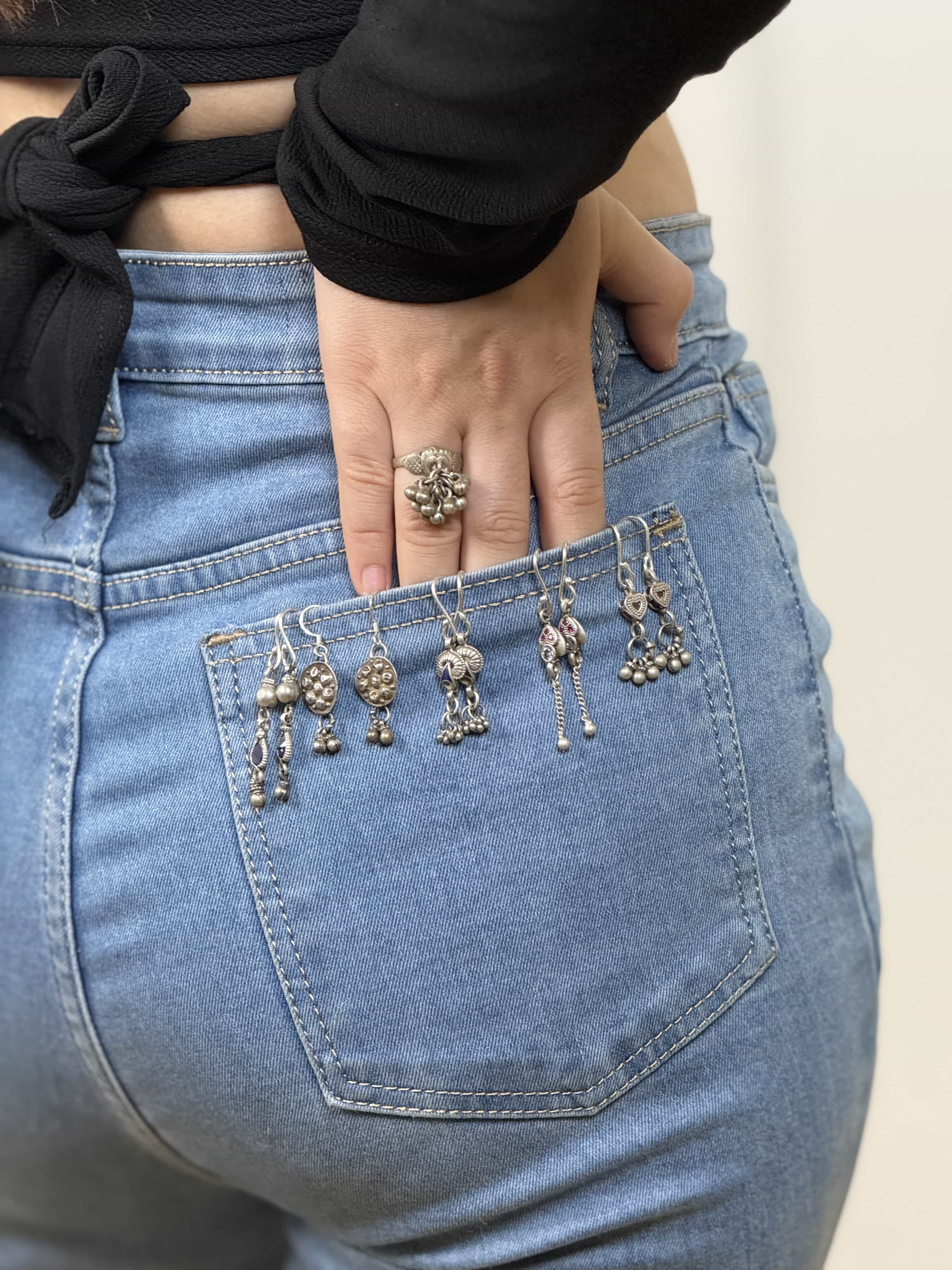 Person wearing blue jeans with vintage silver earrings from Sadabahaar.