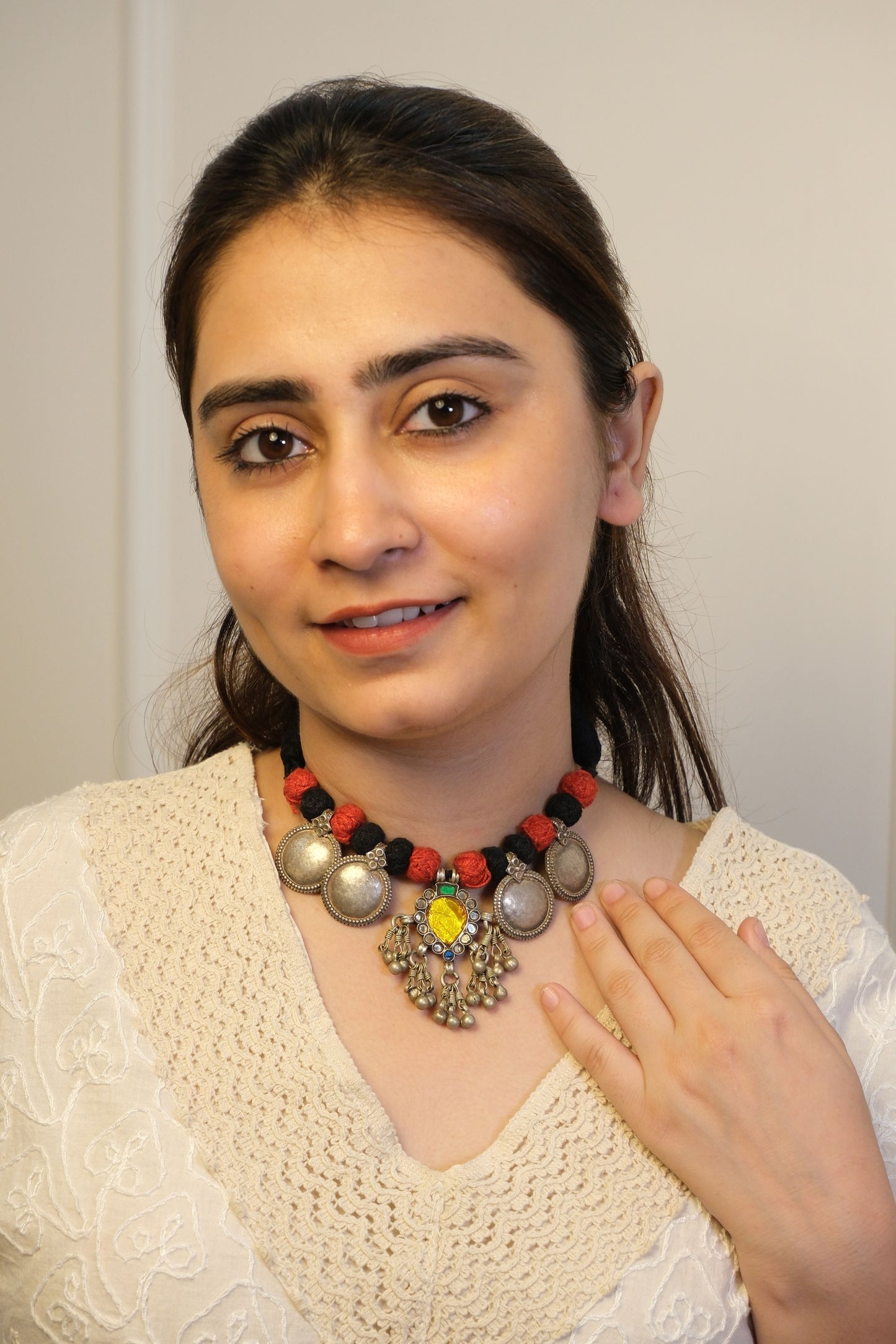 Woman wearing a colorful beaded necklace against a plain background