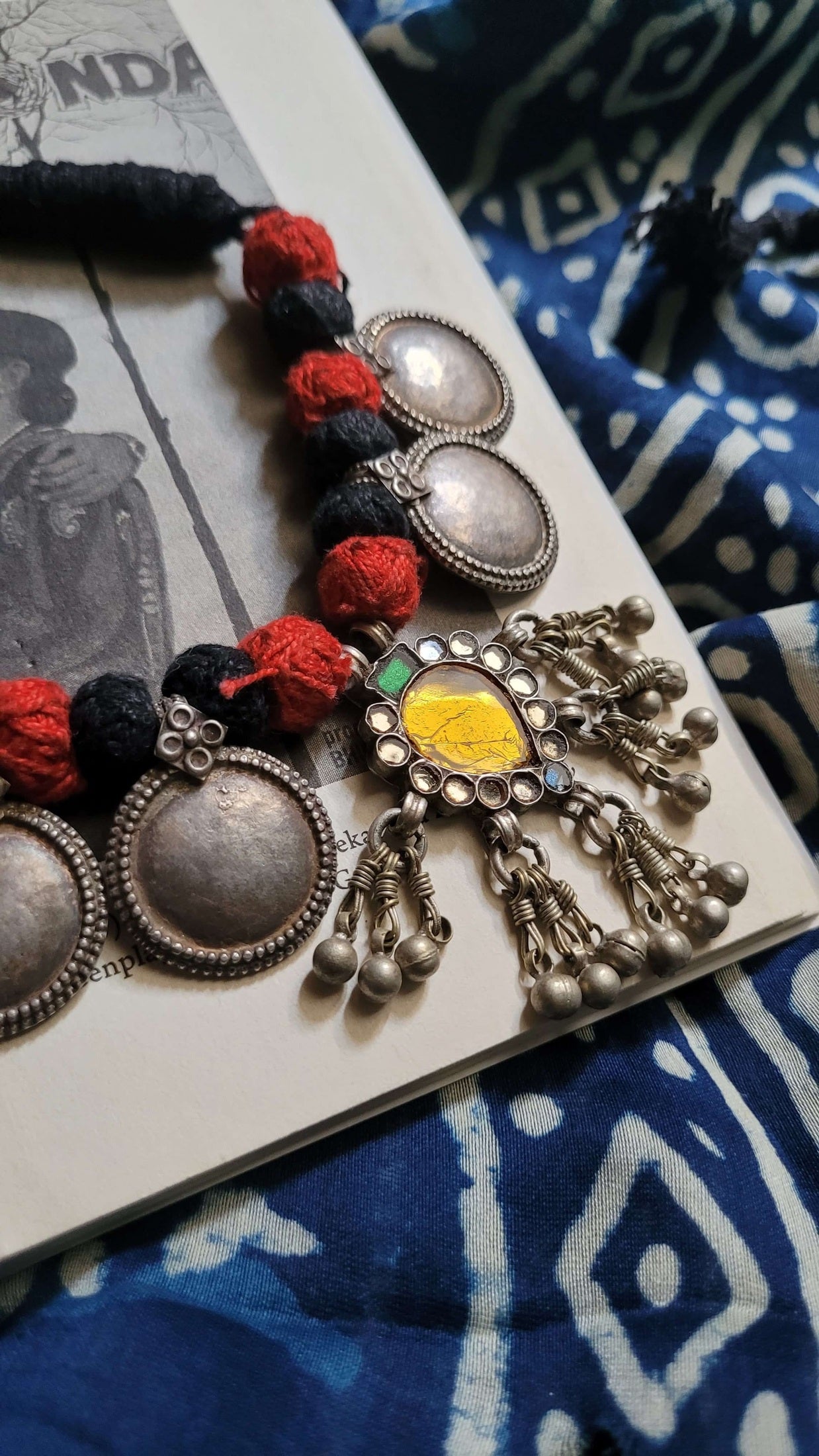 Sunehri Vintage Necklace with colorful beads on a book with a blue patterned fabric background