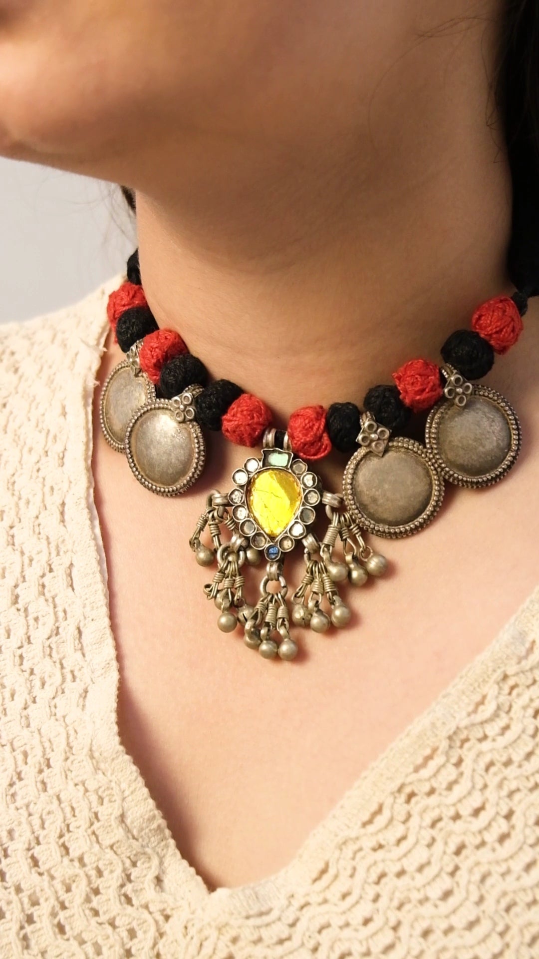 Glass Necklace with red and black beads and decorative elements worn by a person.