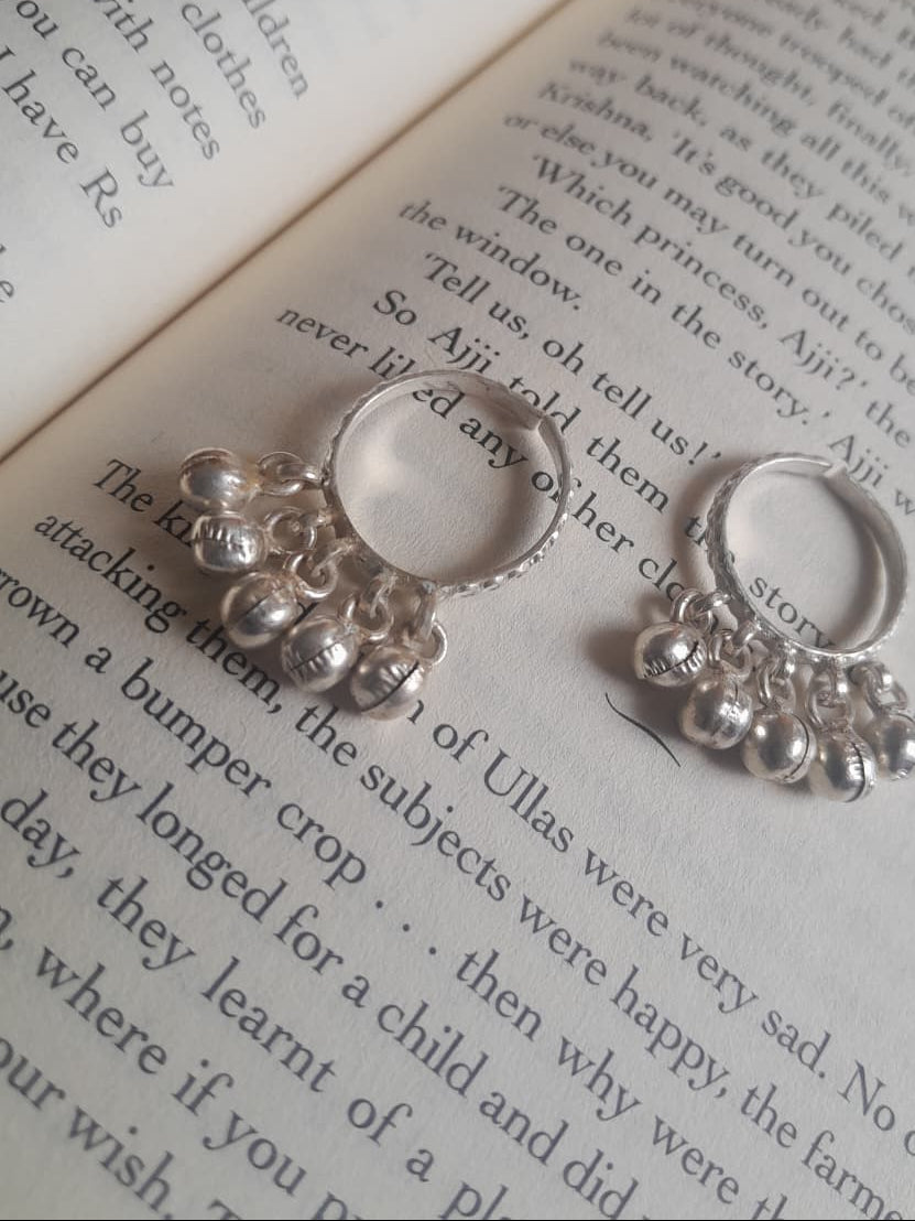 Two silver rings with dangling bead clusters, displayed on the pages of an open book.