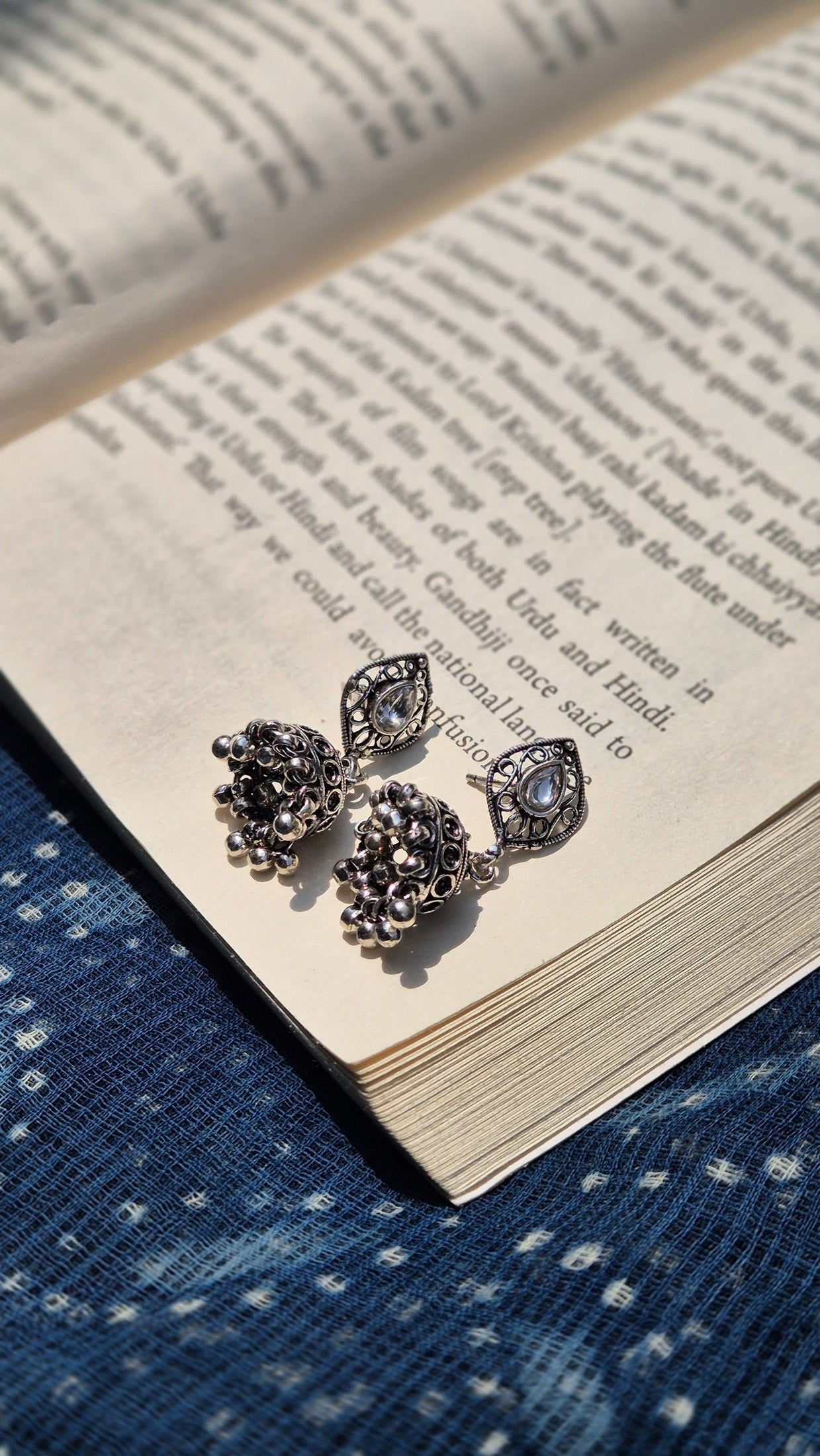 Silver earrings with white gemstones on an open book