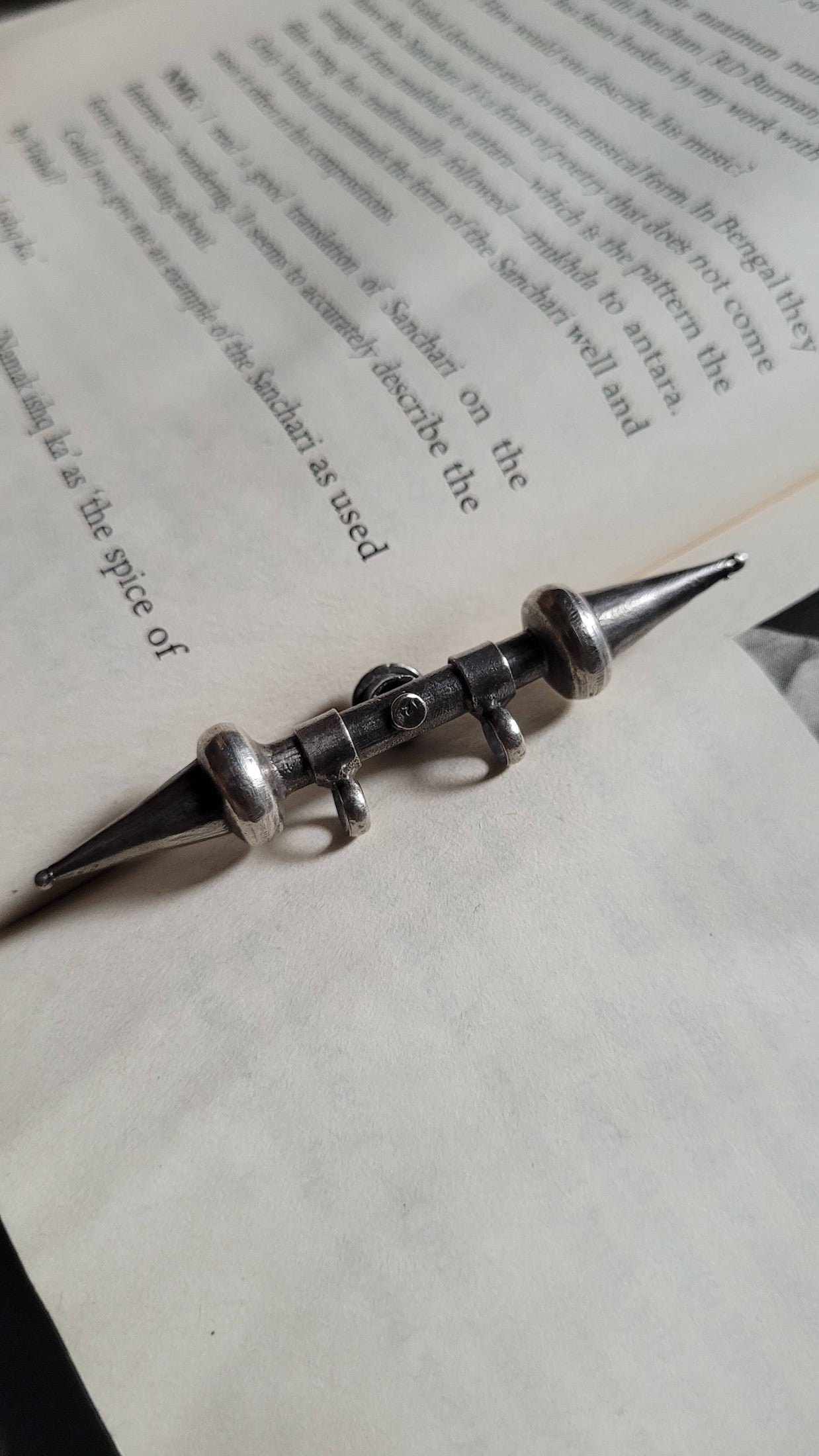 Tavishi Pendant with a decorative top on a book page