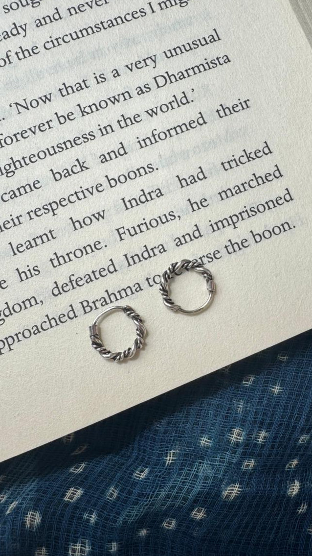 Silver hoops on an open book with a blue fabric background