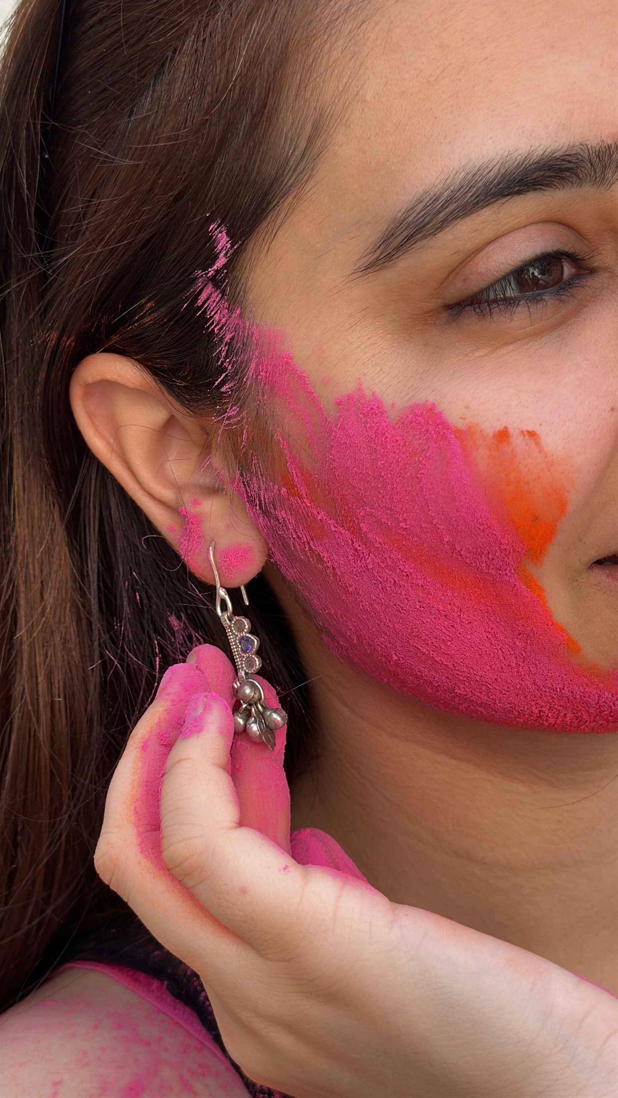 Close-up of a person with colorful face paint and an earring.