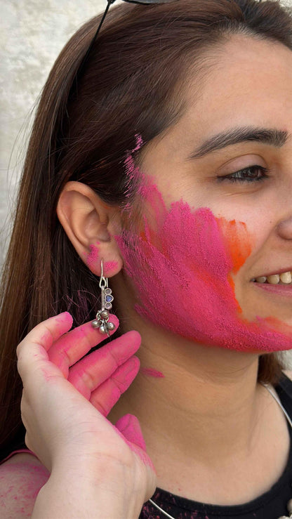 Woman with colorful makeup on her face and neck, wearing a silver earring.
