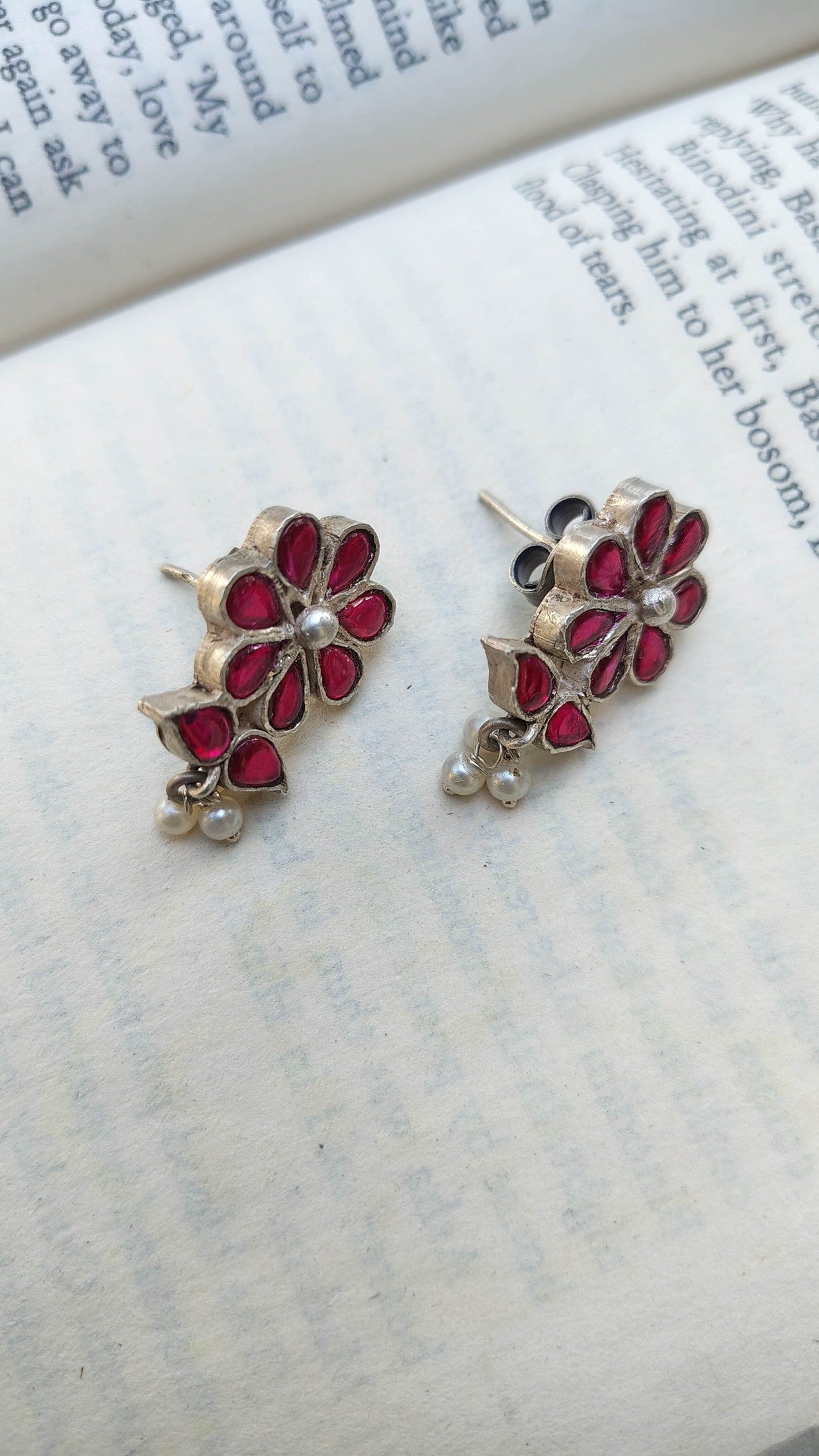 Floral earrings with red stones on a book page